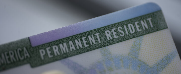Close up view of Fragment of Permanent resident card (Green) card of USA on blurred background.