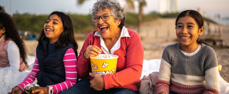 Grandmother with grandchildren watching a movie at the outdoors cinema