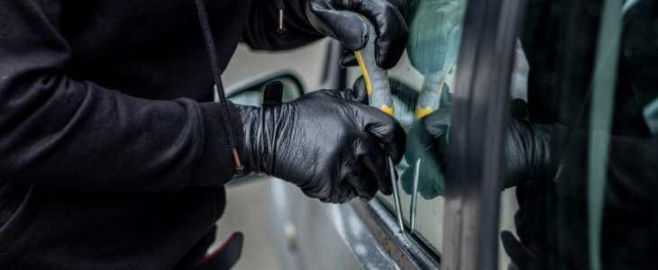 Car thief trying to break into a car with a screwdriver